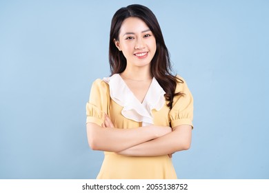 Beautiful Asian young woman wearing yellow dress on blue blackground - Shutterstock ID 2055138752