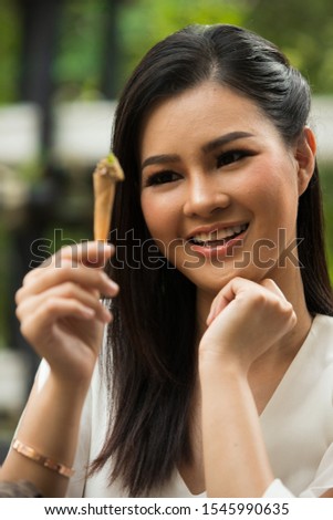 Beautiful Asian Young Woman white short dress pick up small piece of Great spice Idian Fusion food on wooden log bark tree in restaurant, feel smile and happy enjoy eating time.