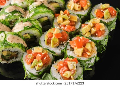 A beautiful assortment of sushi rolls filled with ripe avocado and fresh tomatoes, elegantly displayed on a sleek black surface, highlighting their vibrant colors and textures. - Powered by Shutterstock