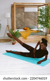 Beautiful Athletic Afro American Woman Lying On Side And Raising Leg Up, Training On Gymnastic Mat In Decorated Photo Studio. Sports Course, Exercise Technique, Fitness, Keeping Body Fit.