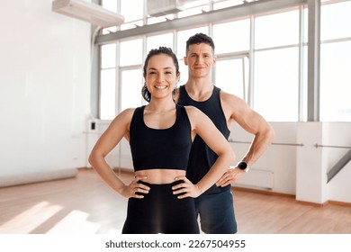 beautiful athletic couple in sportswear stands in the gym in the morning, fitness girl and coach man in training in bright room - Powered by Shutterstock