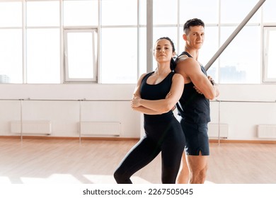 beautiful athletic couple in sportswear stands in the gym in the morning, fitness girl and coach man in training in bright room, copy space - Powered by Shutterstock