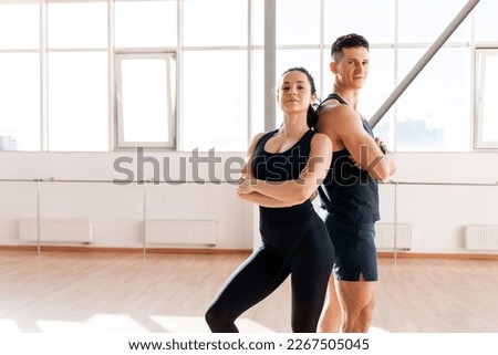 beautiful athletic couple in sportswear stands in the gym in the morning, fitness girl and coach man in training in bright room, copy space Stok fotoğraf © 