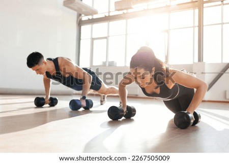 beautiful athletic couple in sportswear in training do push-ups with dumbbells in the fitness room in the morning, man trainer and fitness girl go in for sports in bright room Foto stock © 