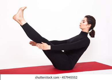 Beautiful athletic girl in black suit doing yoga. naukasana asana - boat pose. Isolated on white background.