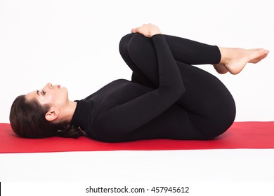 Beautiful athletic girl in a black suit doing yoga. apanasana asana apan pose. Isolated on white background.