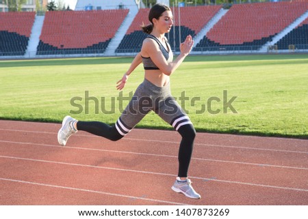 Beautiful athletic girl running around the stadium