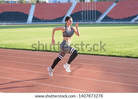 Beautiful athletic girl running around the stadium