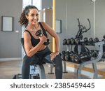 Beautiful athletic muscular woman pumps up the muscles by one arm lifts dumbbell exercise in fitness. Young healthy woman in sportswear doing exercise in fitness.  
