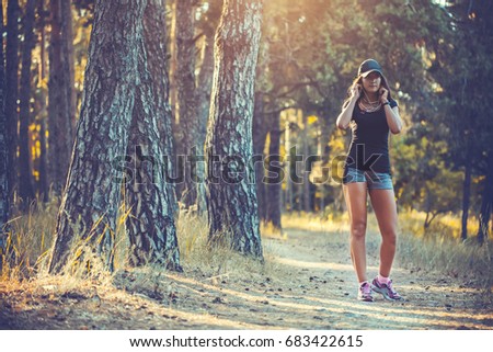 Beautiful athletic woman listening music on a run in the woods