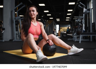 Beautiful Athletic Woman Resting After Doing Sit Ups With Medicine Ball At Sports Studio