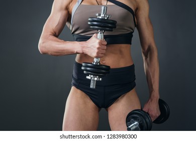 beautiful athletic young woman with muscles doing exercises with dumbbells bodybuilding in the gym