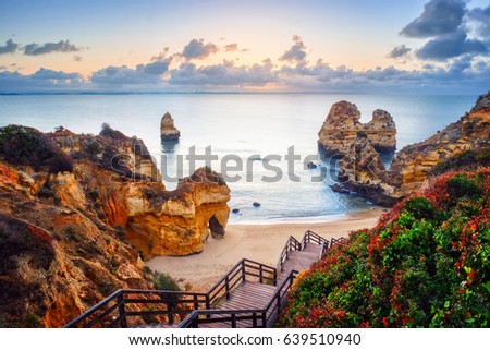 beautiful Atlantic ocean view horizon with sandy beach,  rocks and waves at sunrise. Algarve,  Portugal