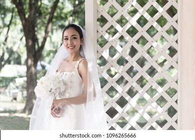 Beautiful Attractive Asian Bride Woman wearing wedding dress and holding bouquet smile and happiness in wedding day - Powered by Shutterstock