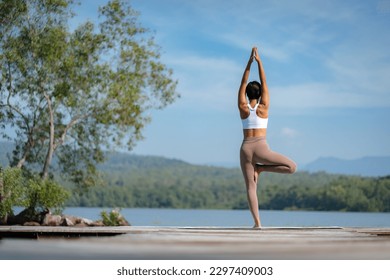 Beautiful attractive Asian woman practice fitness yoga pose on the pool above the Mountain peak in front of nature lake views, Feel so comfortable lifestyle and relax exercise in holiday morning - Powered by Shutterstock