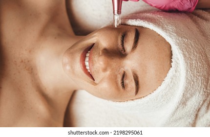 Beautiful Attractive Female Patient Smiling While Receiving Face Oxygen Peeling At Spa Salon. Health Care, Beauty Treatment. Skin Treatment. Aesthetic