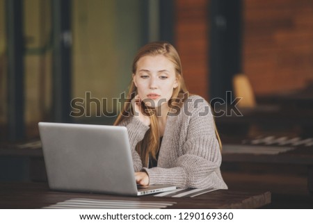 Beautiful attractive girl working in a coffe shop with a laptop
