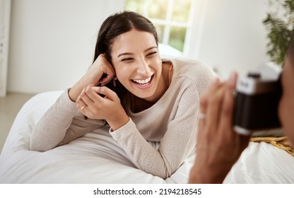 Beautiful, attractive and happy woman having a home photoshoot while lying in bed and smiling. Young excited female having pictures or photos taken while relaxing in her bedroom