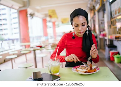 A Beautiful And Attractive Malay Muslim Woman In A Hijab Enjoys Nasi Lemak And Sugarcane Juice For Lunch During The Daytime In A Hawker Center In Singapore. 