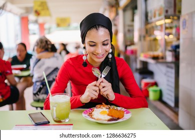 A Beautiful And Attractive Malay Muslim Woman In A Hijab Enjoys Nasi Lemak And Sugarcane Juice For Lunch During The Daytime In A Hawker Center In Singapore. 