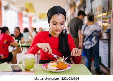 A Beautiful And Attractive Malay Muslim Woman In A Hijab Enjoys Nasi Lemak And Sugarcane Juice For Lunch During The Daytime In A Hawker Center In Singapore. 