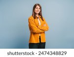 Beautiful, attractive, middle aged woman wearing casual yellow shirt with arms crossed standing isolated on blue background. Confident successful female looking at camera. Business concept