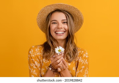 beautiful attractive stylish woman in yellow dress and straw hat holding daisy flower romantic mood posing on yellow background isolated in love summer fashion trend style, natural look - Powered by Shutterstock