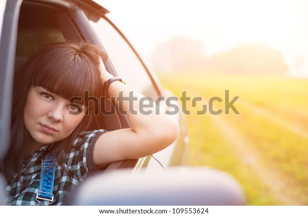 Beautiful attractive woman in car driving on road,\
looking through the\
window