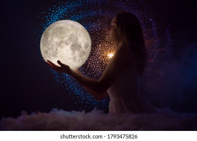 Beautiful attractive woman on a background with stars hugs the moon - Shutterstock ID 1793475826