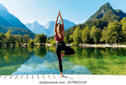 beautiful attractive woman practice yoga, standing on wooden pier looking at green lake and mountain - Powered by Shutterstock