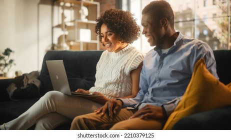 Beautiful Authentic Couple In Cozy Living Room Making A Video Call On Laptop Computer At Home. Spouses Chatting With Relatives Or Close Friends Over The Internet On Social Networks.