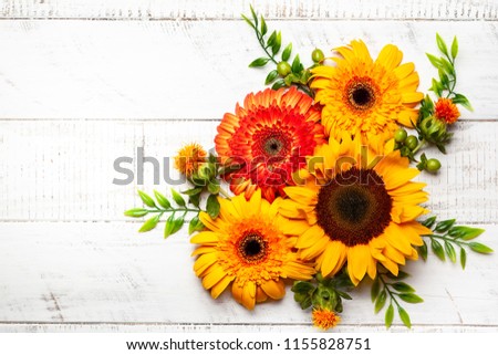 Beautiful autumn flowers and berries on the white wooden background. Top view with copy space. Autumnal concept.