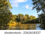 a beautiful autumn landscape along the Chattahoochee River with silky brown water and autumn colored trees, blue sky and clouds at Chattahoochee River National Recreation Area in Sandy Springs Georgia