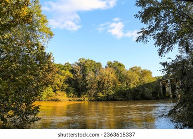 a beautiful autumn landscape along the Chattahoochee River with silky brown water and autumn colored trees, blue sky and clouds at Chattahoochee River National Recreation Area in Sandy Springs Georgia - Shutterstock ID 2363618337