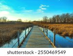 Beautiful Autumn landscape captured at Horicon Marsh in Dodge County, Wisconsin, of a late-afternoon sky beyond a wooden boardwalk and forest of bare trees.