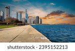 A beautiful autumn landscape at Lakefront Park with the rippling blue waters of Lake Michigan, autumn trees, people walking, skyscrapers and office buildings, blue sky and clouds in Chicago Illinois