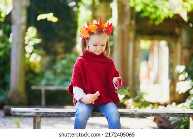 Beautiful autumn portrait of adorable preschooler girl in colorful maple leaves wreath on her head