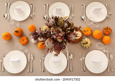 Beautiful autumn table setting with pumpkins and protea flowers at restaurant