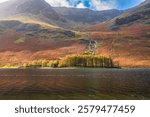 Beautiful autumn trees with Haystacks peak at the shore of Buttermere lake in Lake District. UK