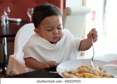 Beautiful Baby Boy Eating Fish And Chip In Restaurant.