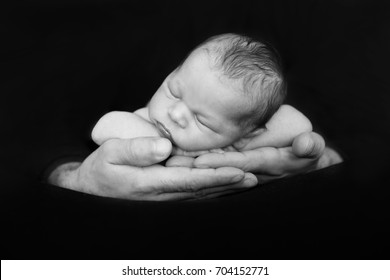 Beautiful baby boy, sleeping peacefully in fathers hands, infant sleeping, isolated image, black background, fathers love, tenderness, family concept