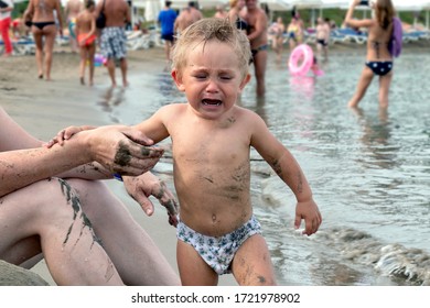 Beautiful Baby Crying On The Beach. A 1-2 Year Old Child Holds Father By The Hand And Cries. Toned.