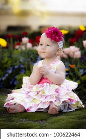Beautiful baby in Easter Dress sitting in Flower Garden