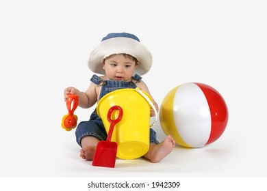 Beautiful Baby Girl In Denim Outfit And Sunhat Playing With Beach Toys.