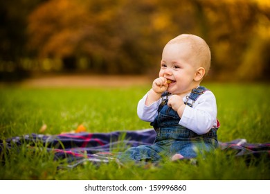 Beautiful Baby Girl Eating Food Outdoor In Nature