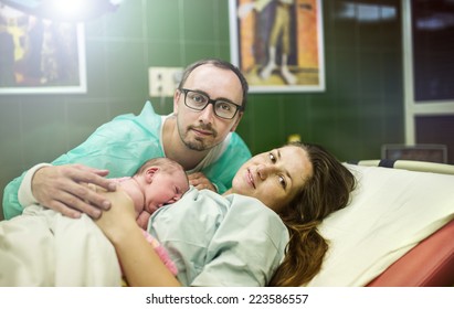 Beautiful Baby Girl Few Minutes After The Birth With Her Mother And Father In Hospital Room, Skin To Skin Contact