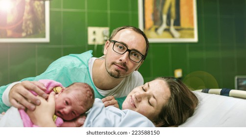 Beautiful Baby Girl Few Minutes After The Birth With Her Mother And Father In Hospital Room, Skin To Skin Contact