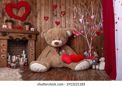 beautiful backdrop for a Valentine's Day photo shoot with a huge teddy bear, a wooden fireplace with candles and flowers, and a tree with red and pink hearts. Romantic mood for the holiday of lovers.