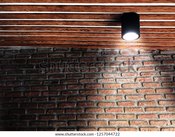 レンガ壁 木の天井 黒い天井ランプを備えたロフトスタイルの美しい背景 レンガ壁の背景に製品またはハイライトアイテムを配置するスポットライト ショップデコーロフトスタイル の写真素材 今すぐ編集