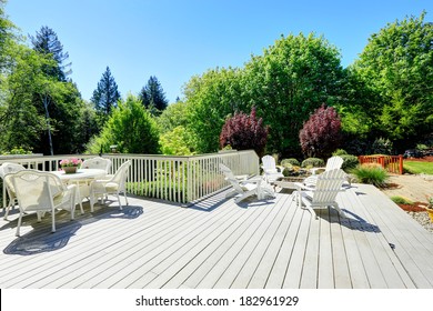 Beautiful Backyard Deck With White Wicker Table Set, Fire Pit And Chairs.